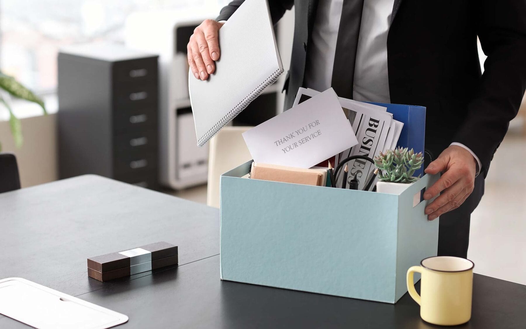 Man packing office items in a box at his desk