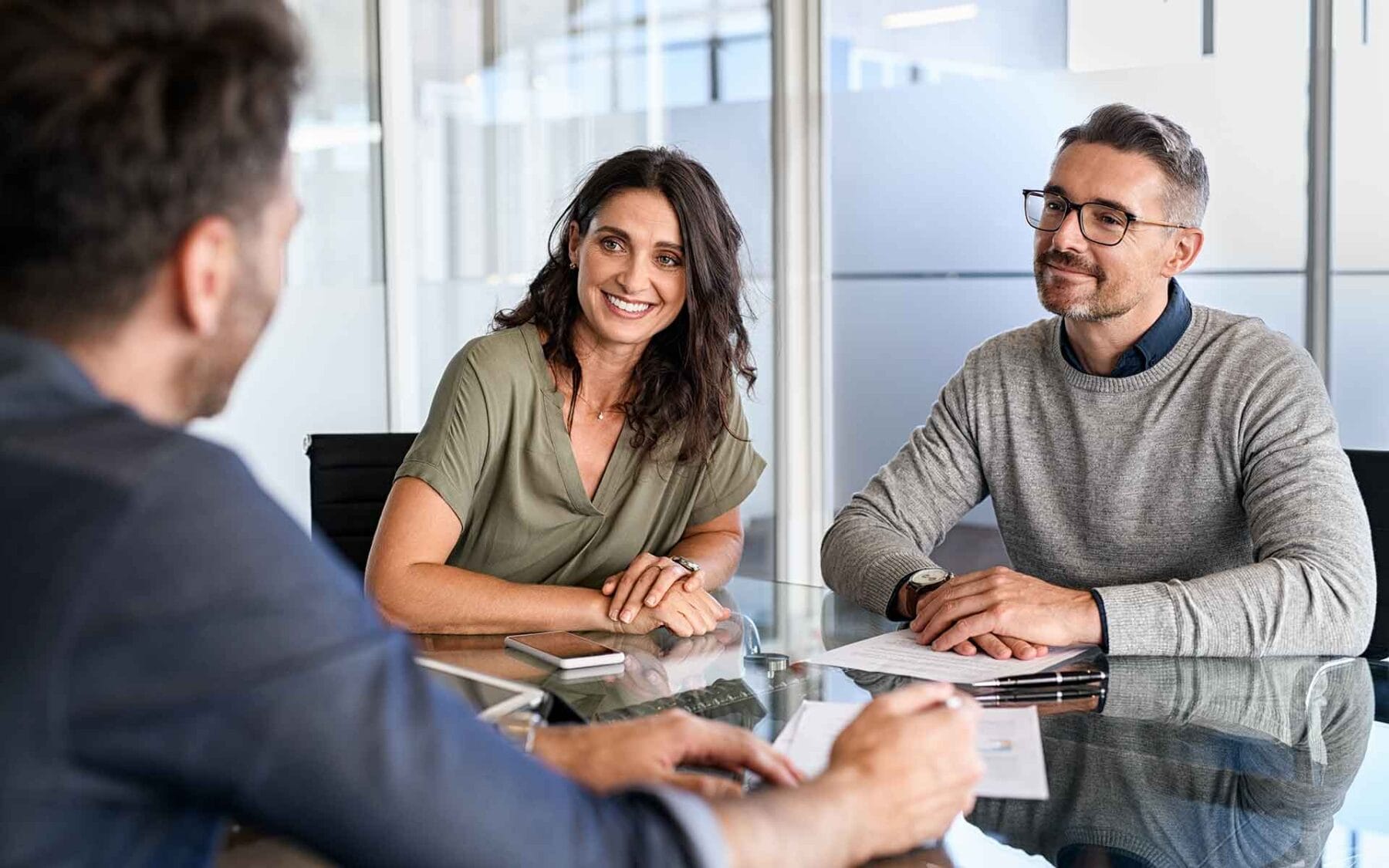 Professional couple discussing sitting at desk with business owner